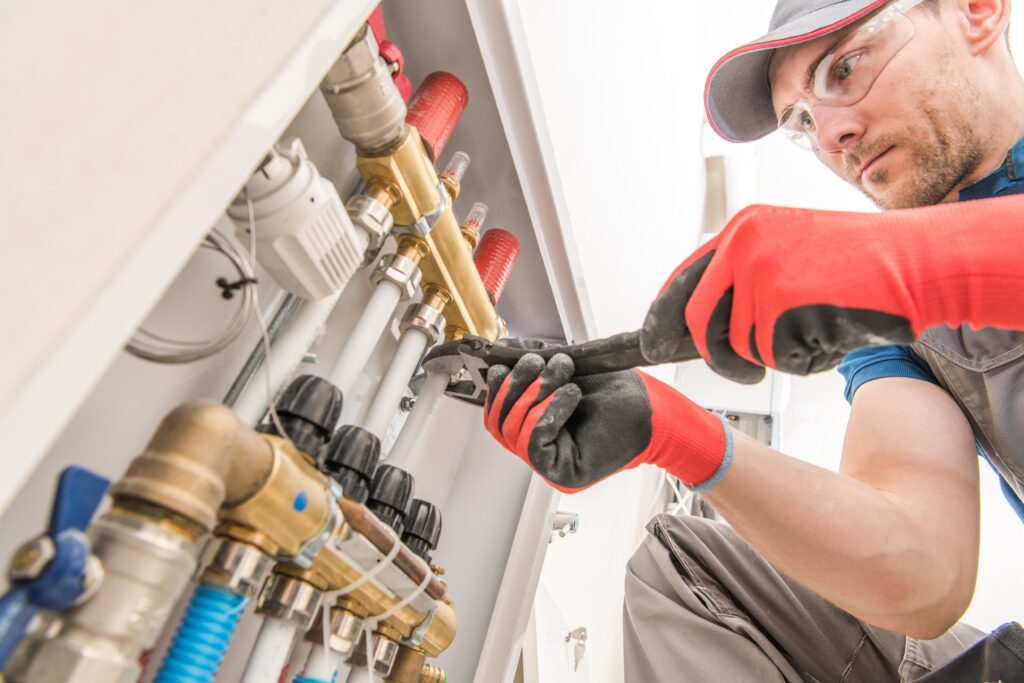 Installateur am Heizkreisverteiler einer Fußbodenheizung